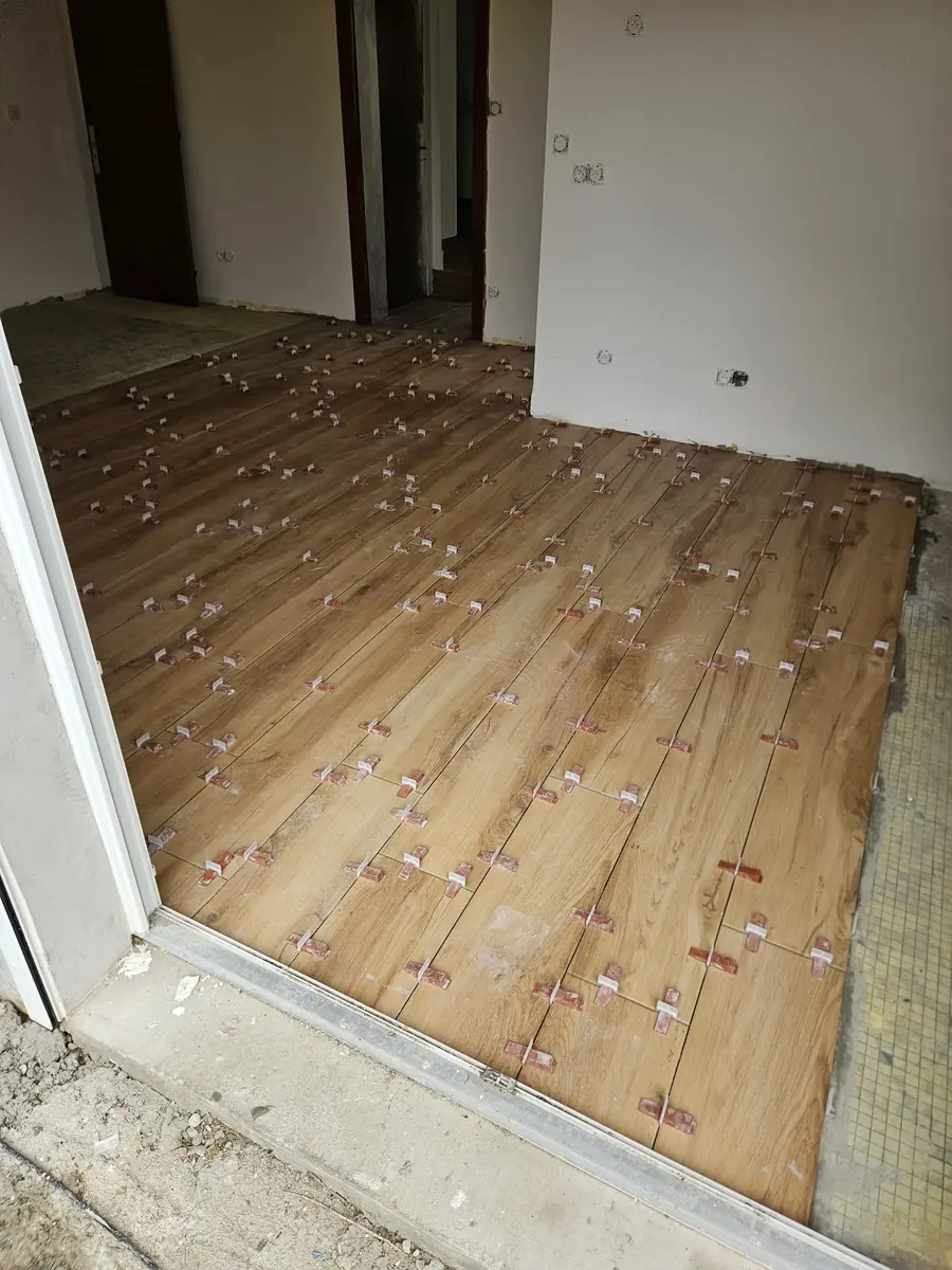Carrelage en cours de pose. Croisillons autonivelants et calepinage au droit du seuil.