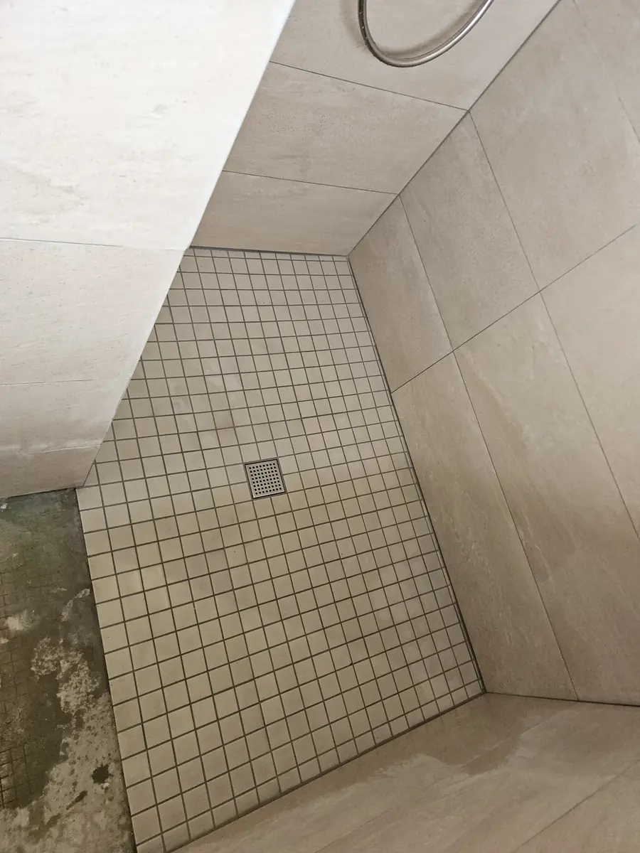 Receveur de douche carrelé. Mosaïque suivant la pente, siphon de sol centré.