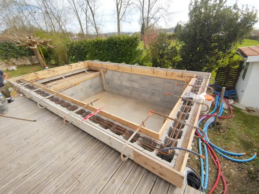 Piscine béton — structure. Blocs à bancher, ceinture ferraillée, coffrage des margelles.