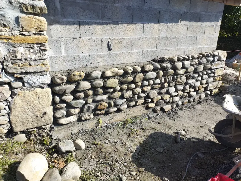 Soubassement en galets. Reprise du pied de mur sous une élévation en blocs.